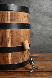 Photo of Corkscrew with metal handle, cork and wooden barrel on table