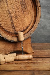 Photo of Corkscrew, corks and wooden barrel on table, closeup