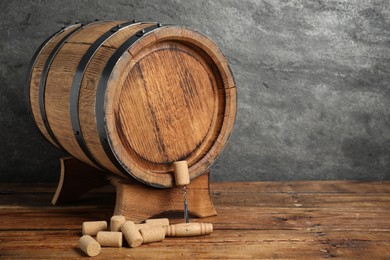 Photo of Corkscrew, corks and wooden barrel on table, space for text