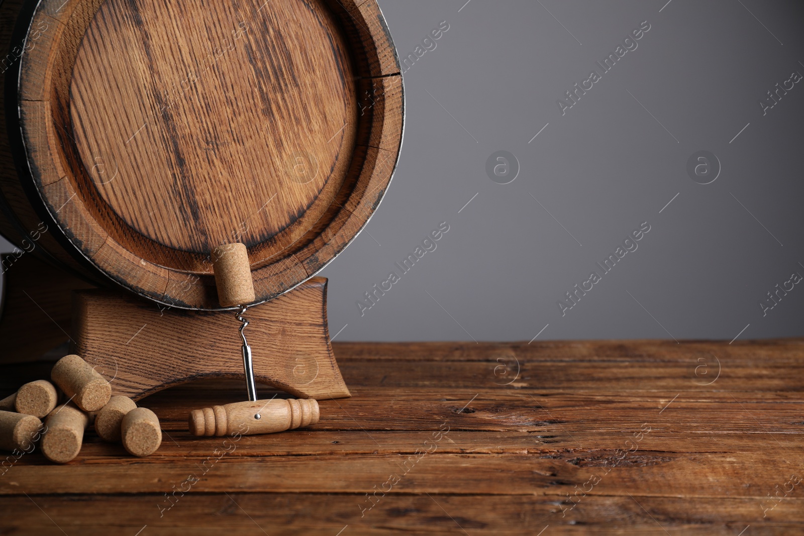 Photo of Corkscrew, corks and wooden barrel on table, space for text