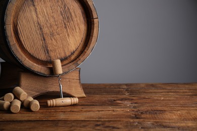 Photo of Corkscrew, corks and wooden barrel on table, space for text