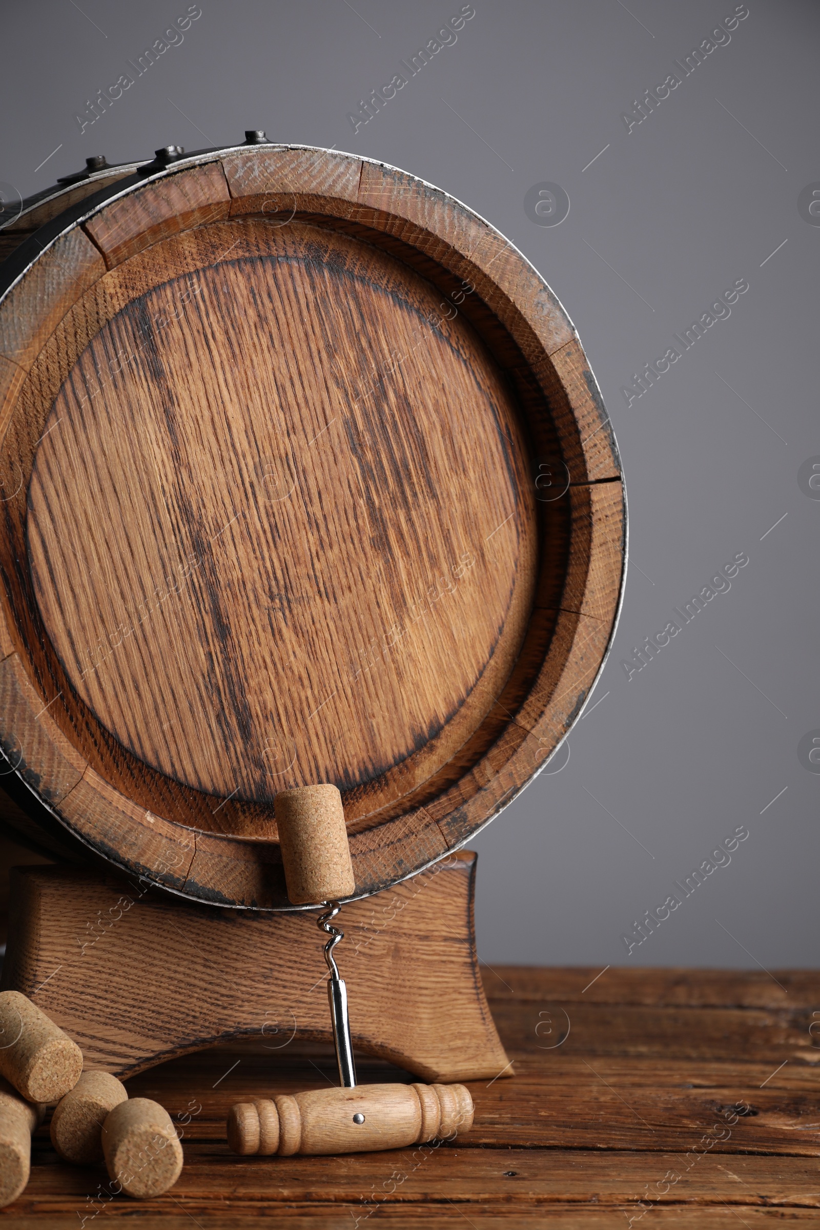 Photo of Corkscrew, corks and wooden barrel on table