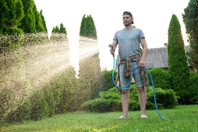 Man watering lawn with hose in backyard, low angle view