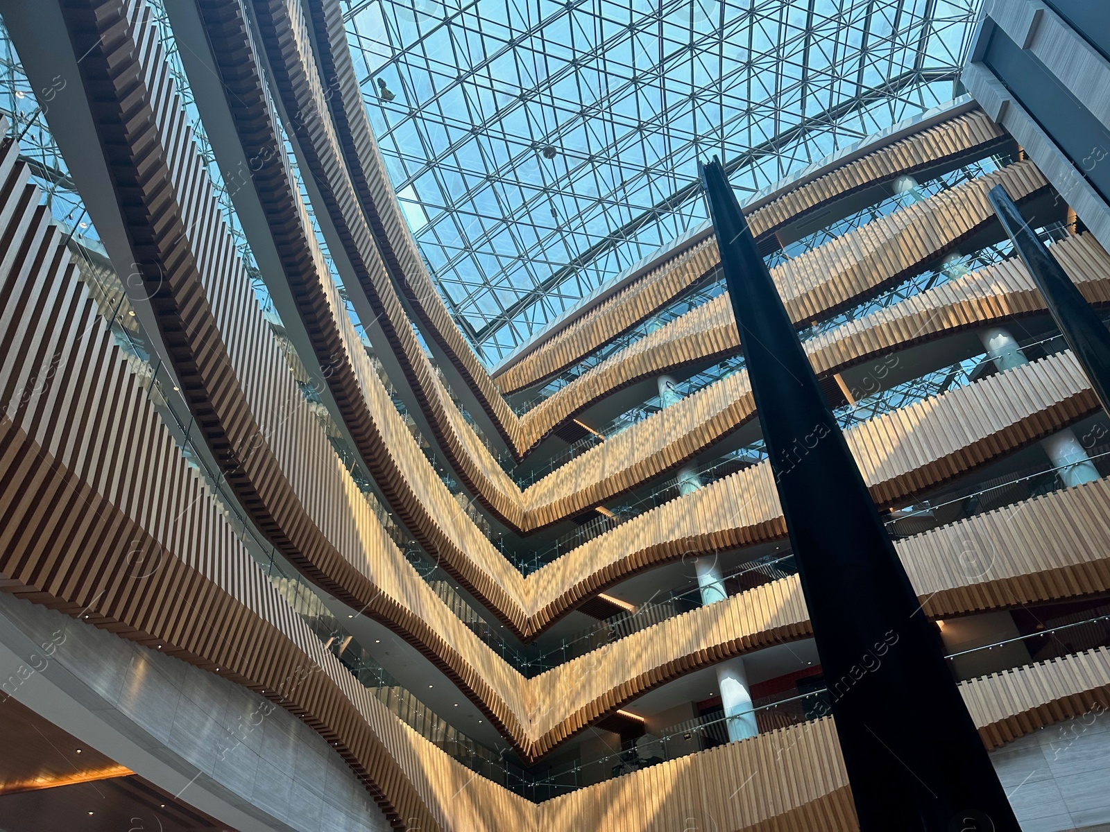 Photo of Interior of luxury hotel with many floors and glass roof, low angle view