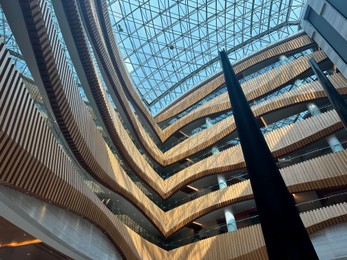 Interior of luxury hotel with many floors and glass roof, low angle view