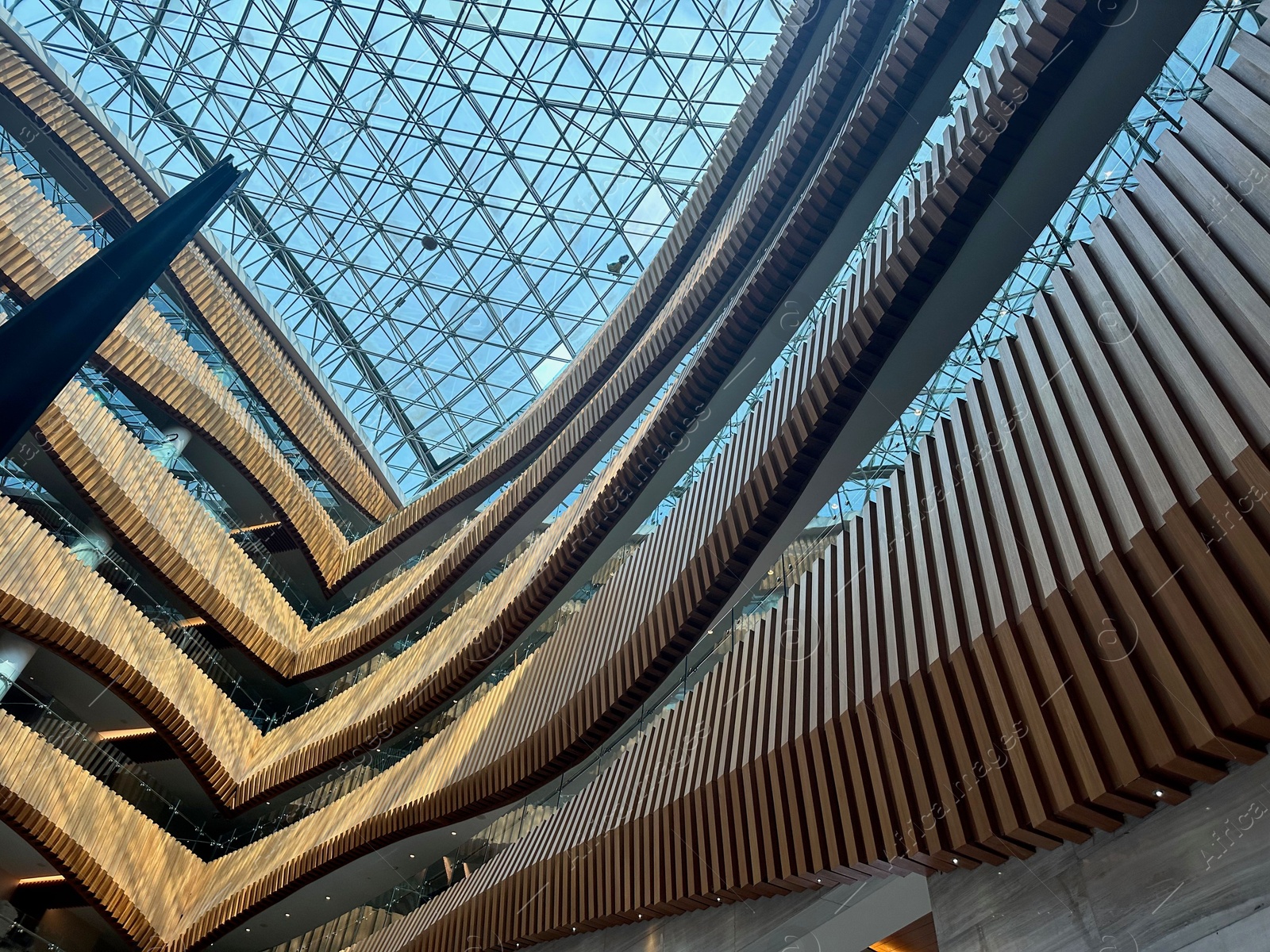 Photo of Interior of luxury hotel with many floors and glass roof, low angle view