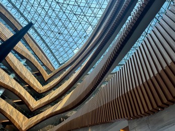 Interior of luxury hotel with many floors and glass roof, low angle view