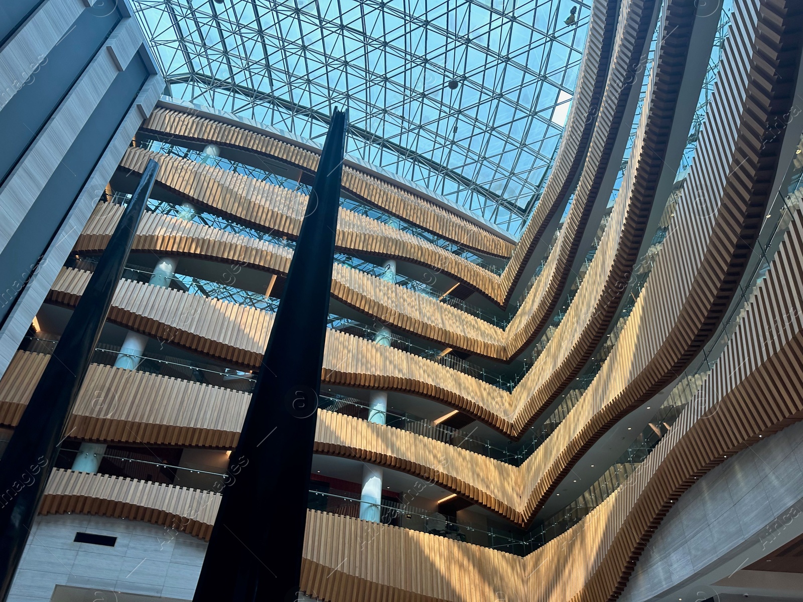 Photo of Interior of luxury hotel with many floors and glass roof, low angle view