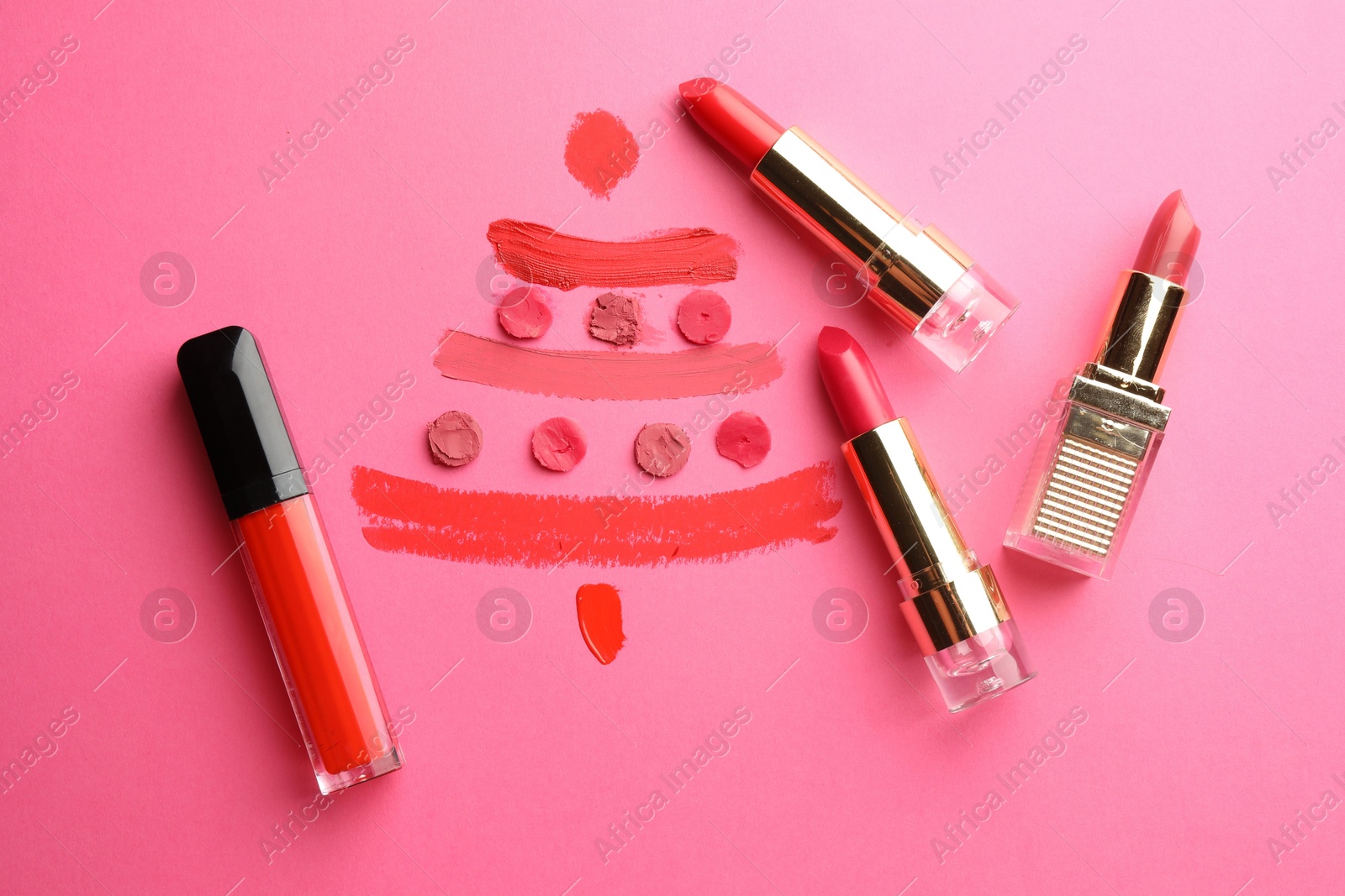 Photo of Christmas tree drawn with lipsticks on pink background, flat lay