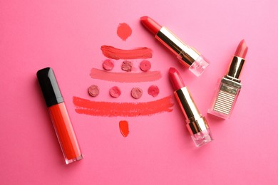 Christmas tree drawn with lipsticks on pink background, flat lay