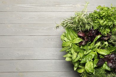 Photo of Different fresh herbs in basket on light grey wooden table, top view. Space for text