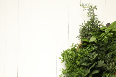 Photo of Different fresh herbs in basket on white wooden table, top view. Space for text