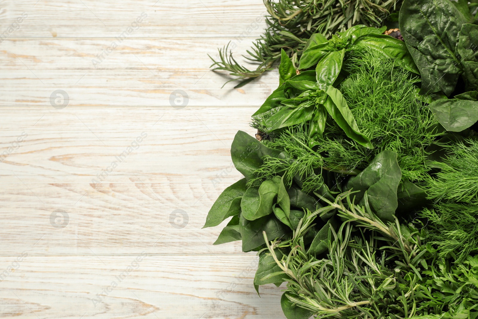 Photo of Different fresh herbs in basket on white wooden table, top view. Space for text