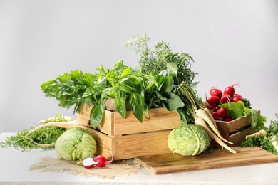 Photo of Different fresh herbs, cabbages and radishes on white table