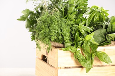 Photo of Different fresh herbs in wooden basket on light grey background, closeup