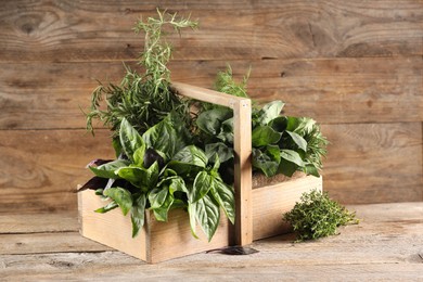 Photo of Different fresh herbs in basket on wooden table