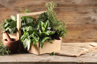 Photo of Different fresh herbs in basket on wooden table, space for text