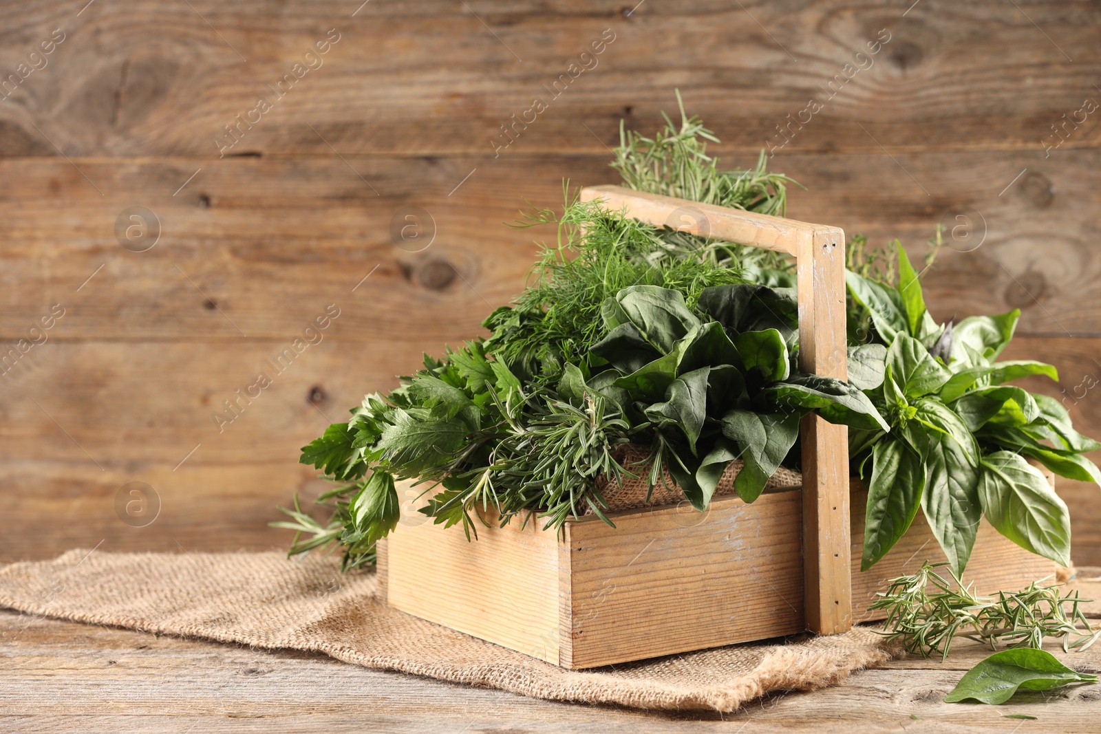 Photo of Different fresh herbs in basket on wooden table, space for text