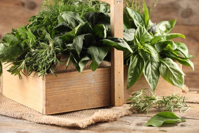 Photo of Different fresh herbs in basket on wooden table, closeup