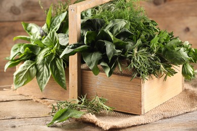 Photo of Different fresh herbs in basket on wooden table, closeup