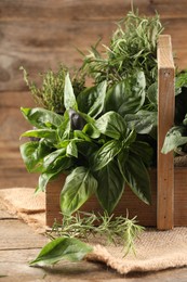 Photo of Different fresh herbs in basket on wooden table, closeup