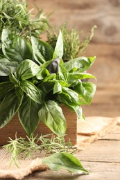 Photo of Different fresh herbs in basket on wooden table, closeup