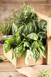 Photo of Different fresh herbs in basket on wooden table, closeup