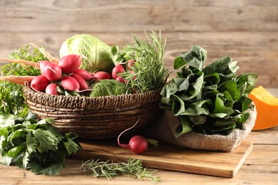 Photo of Different fresh herbs, cabbages, radishes and pumpkin on wooden table