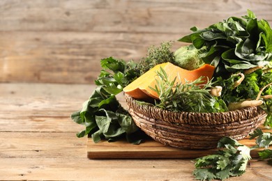 Photo of Different fresh herbs and pumpkin on wooden table, space for text