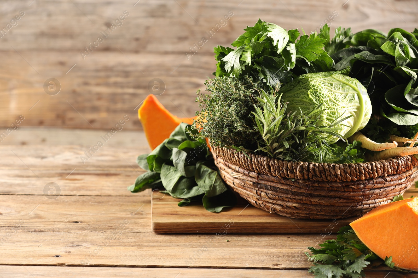 Photo of Different fresh herbs, cabbages and pumpkin on wooden table, space for text