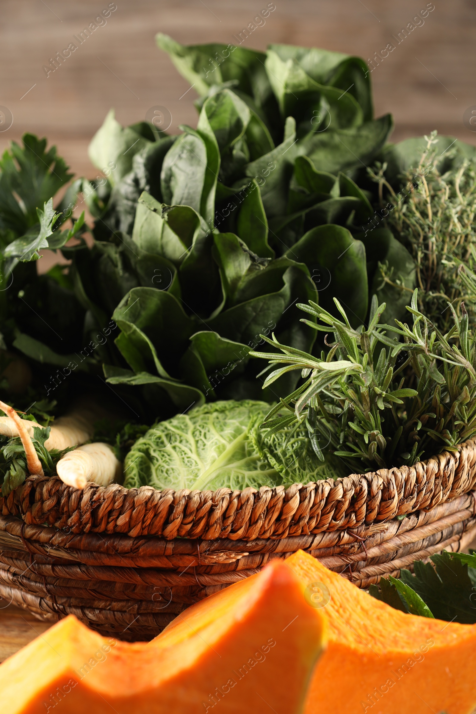 Photo of Different fresh herbs and pumpkin on wooden table, closeup