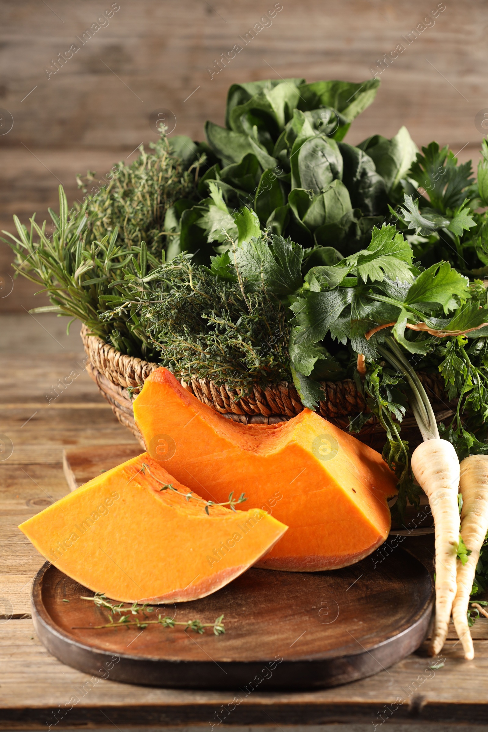 Photo of Different fresh herbs and pumpkin on wooden table