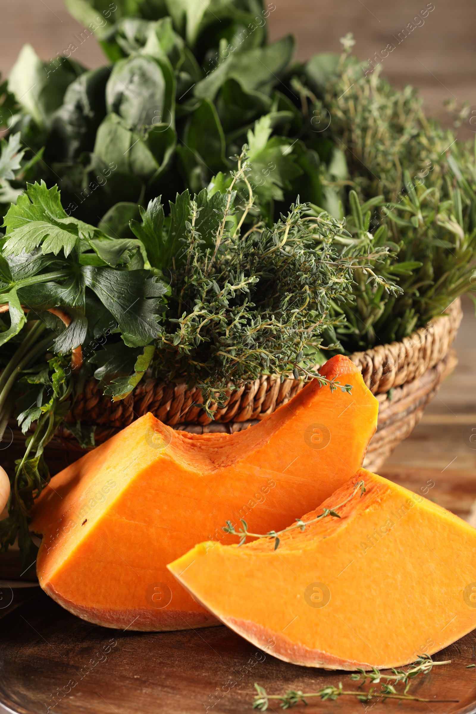 Photo of Different fresh herbs and pumpkin on wooden table, closeup