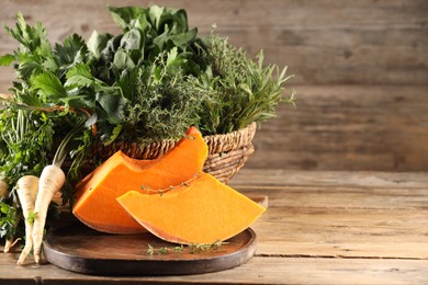 Different fresh herbs and pumpkin on wooden table, space for text