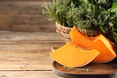 Photo of Different fresh herbs and pumpkin on wooden table, closeup. Space for text