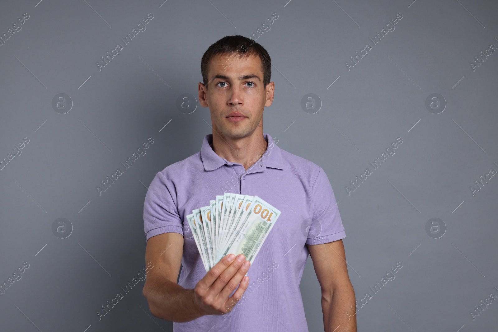 Photo of Man with dollar banknotes on grey background