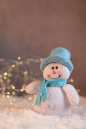 Photo of Funny snowman figure on artificial snow against blurred lights