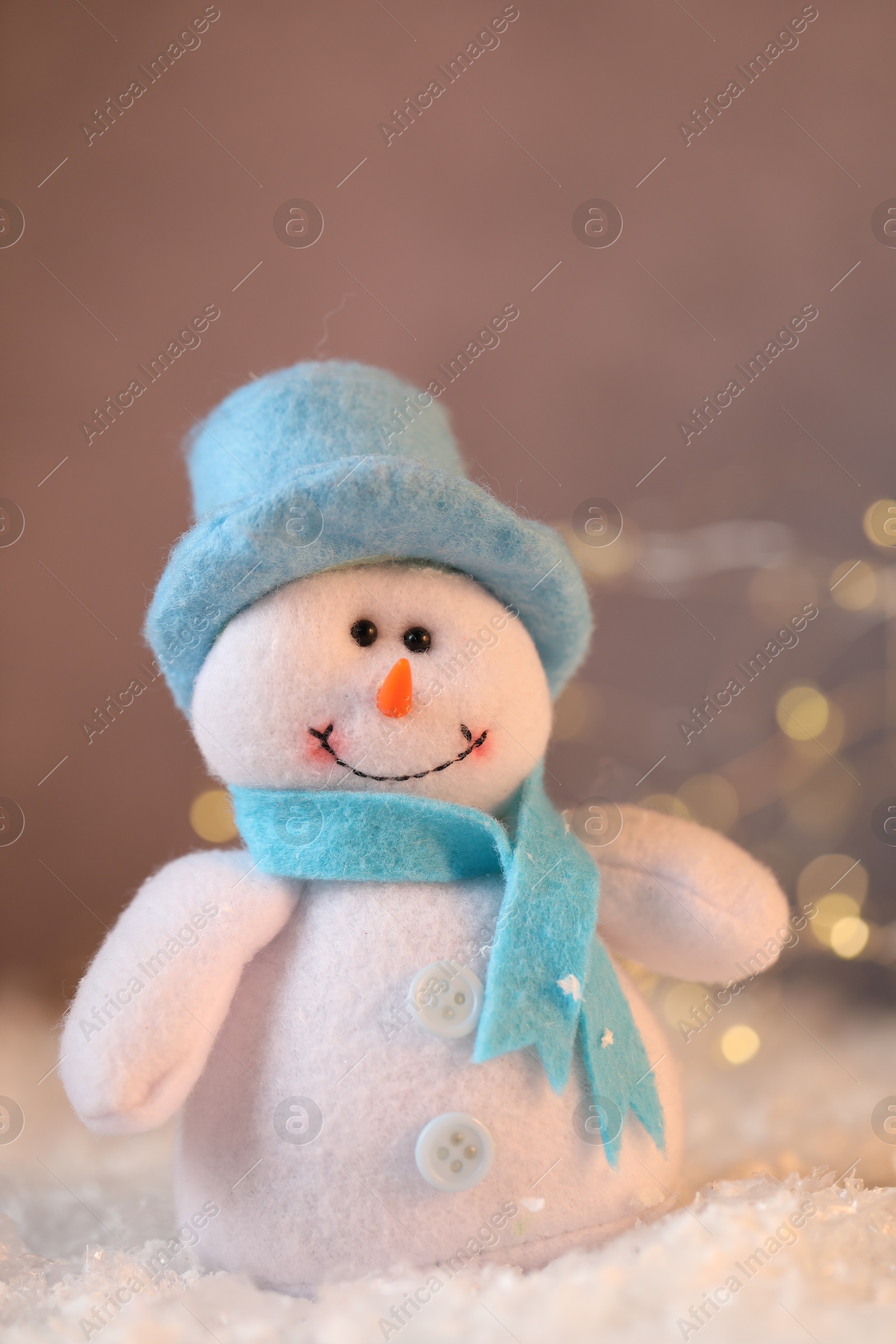 Photo of Funny snowman figure on artificial snow against blurred lights