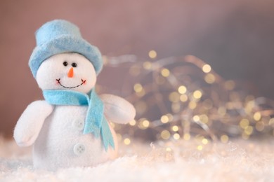 Photo of Funny snowman figure on artificial snow against blurred lights