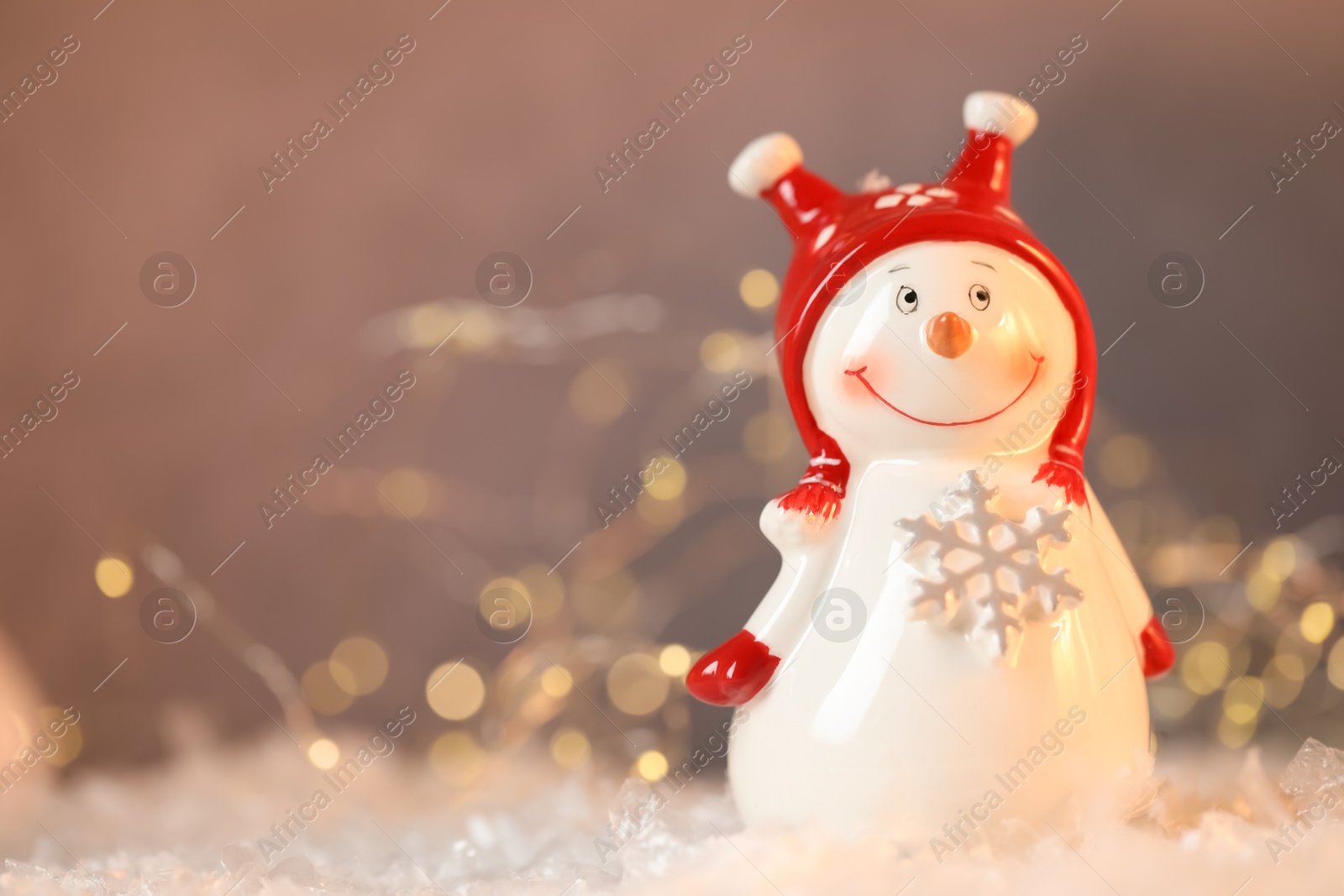 Photo of Funny snowman figure on artificial snow against blurred lights