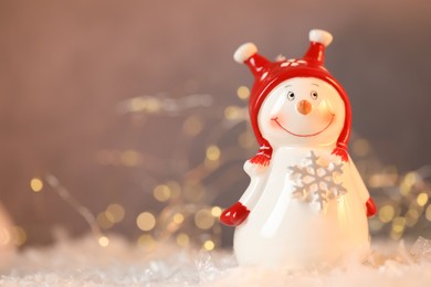 Photo of Funny snowman figure on artificial snow against blurred lights