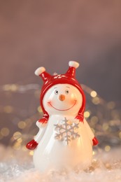 Photo of Funny snowman figure on artificial snow against blurred lights