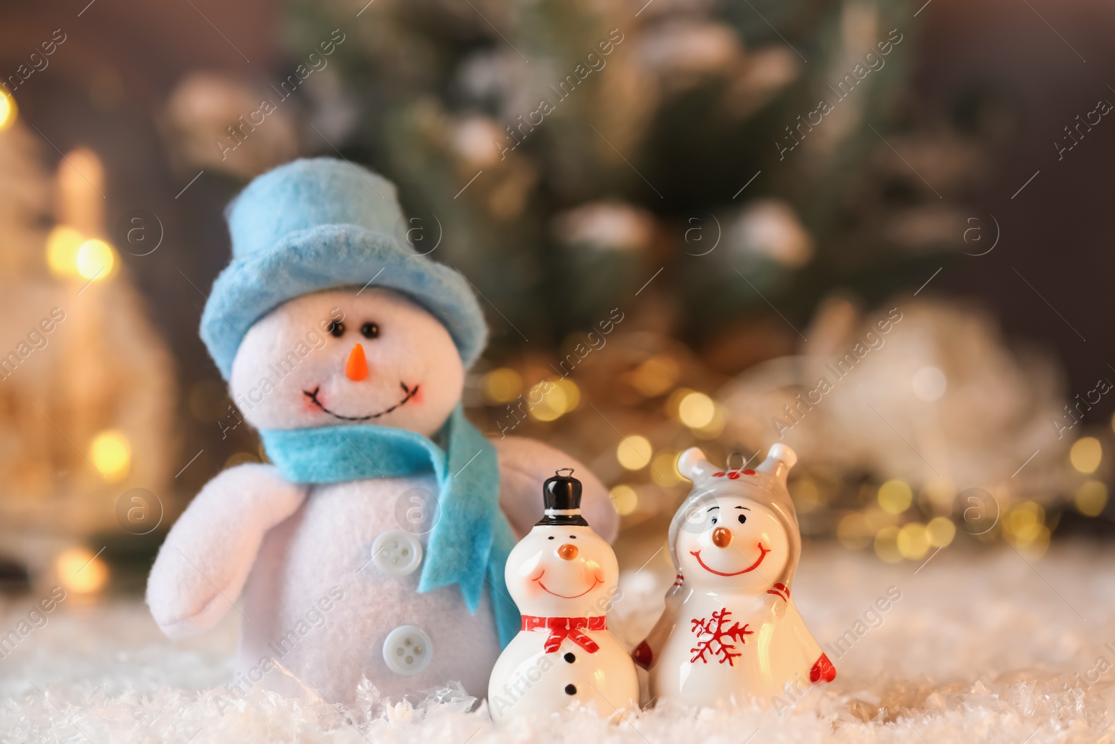 Photo of Funny snowman figures on artificial snow against blurred background