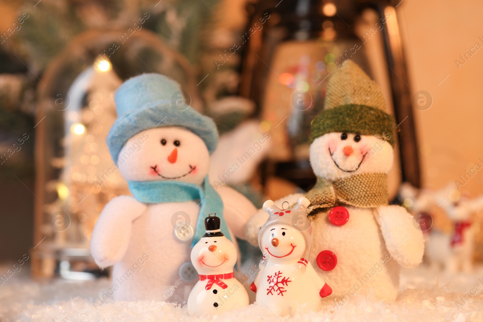 Photo of Funny snowman figures on artificial snow against blurred background