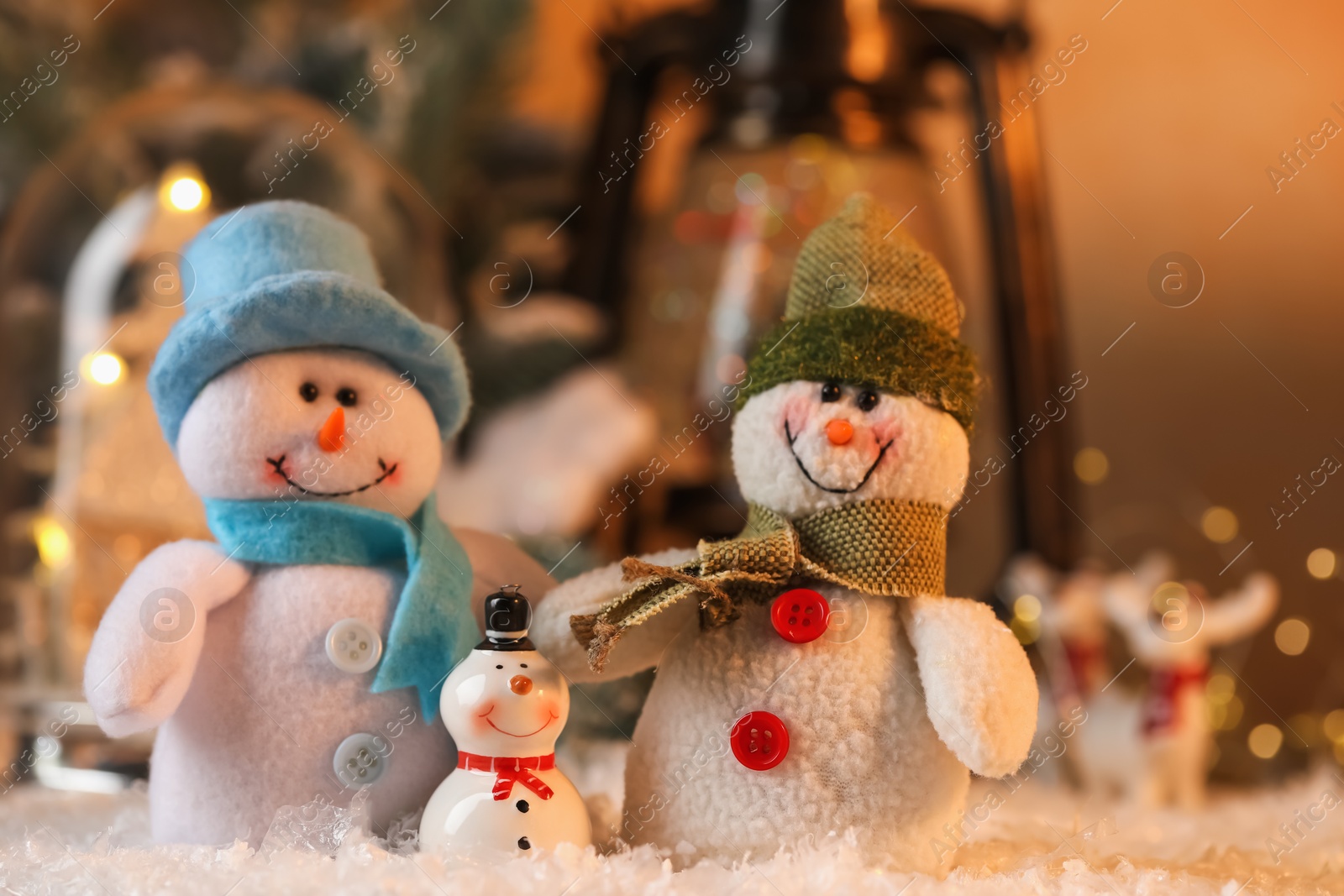 Photo of Funny snowman figures on artificial snow against blurred background