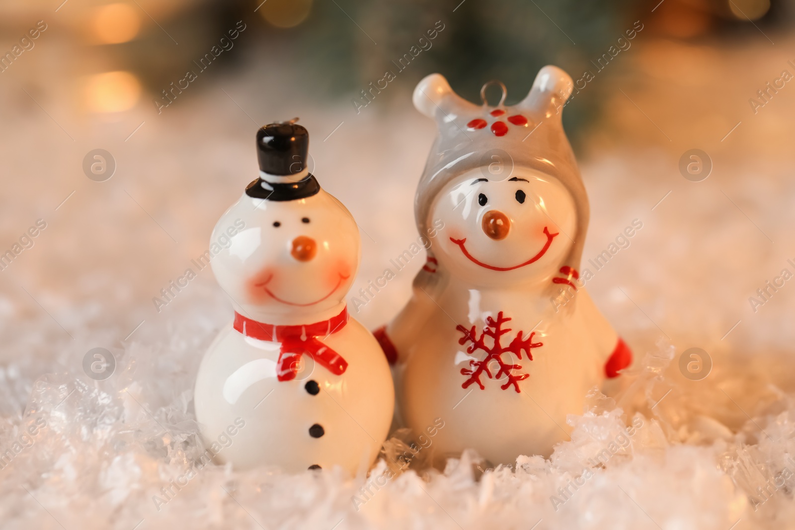 Photo of Funny snowman figures on artificial snow against blurred background, closeup