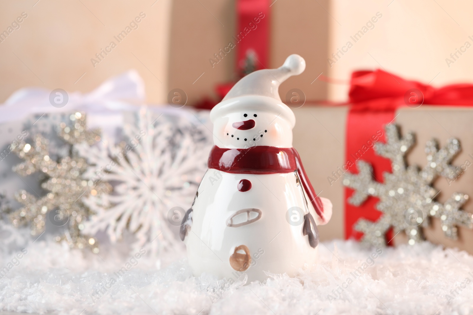 Photo of Funny snowman figure and gifts on artificial snow