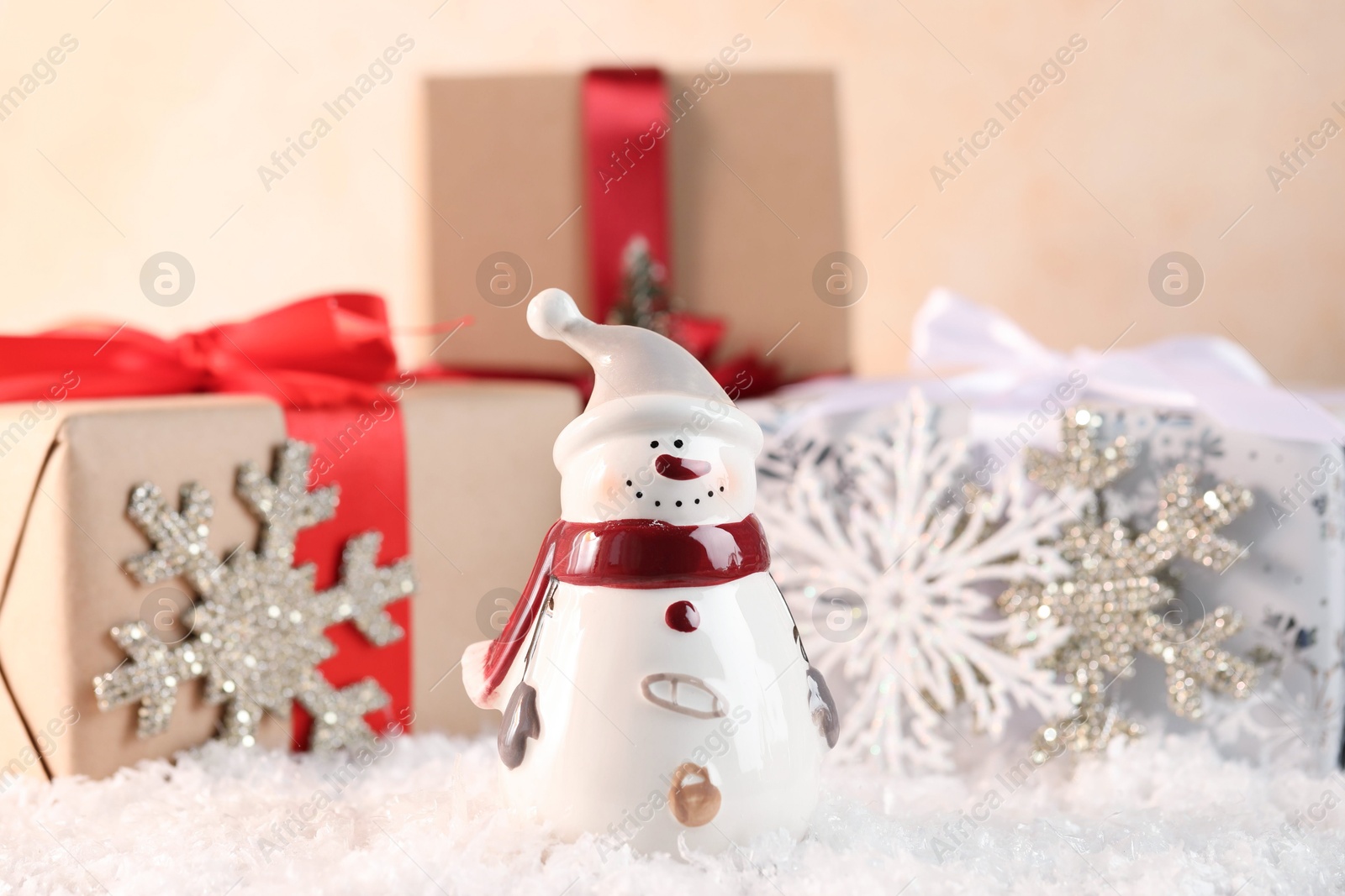 Photo of Funny snowman figure and gifts on artificial snow