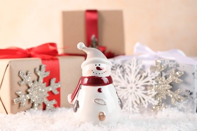 Photo of Funny snowman figure and gifts on artificial snow