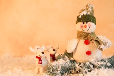 Photo of Funny snowman and deer figures with fir branch on artificial snow